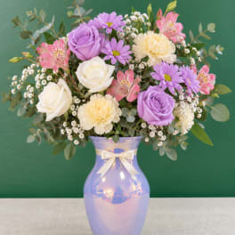 Lavender and white roses with pink and purple flowers in a iridescent vase