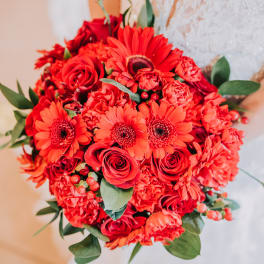 Bride holding a red bouquet with roses and gerbera daisies