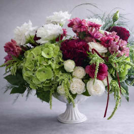 Mixed bouquet in a white pedestal vase with green hydrangea, white roses, and pink blooms