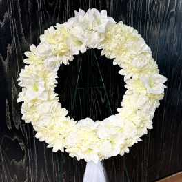 White floral wreath on a stand with a tulle ribbon