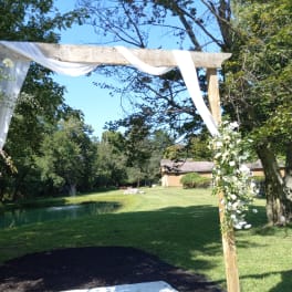 White floral arch draped with sheer fabric outdoors