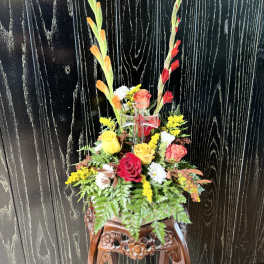 Tall floral arrangement with roses and gladiolus in a clear vase