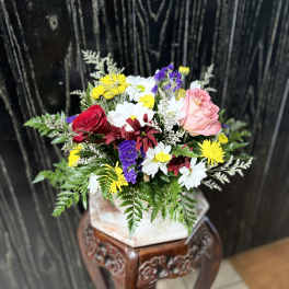 Mixed bouquet with roses and daisies in a square vase