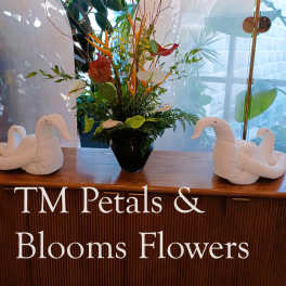 Tropical flower arrangement in a black vase with white swan decorations