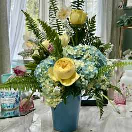 Blue vase with yellow roses and blue hydrangeas