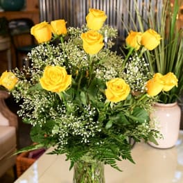 Yellow roses arranged in a clear glass vase with baby's breath