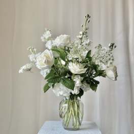 White roses and filler flowers in a clear glass vase