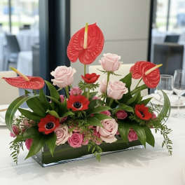 Pink roses and red anthuriums in a rectangular glass vase