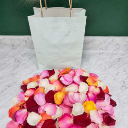 Pile of multicolored rose petals in front of white paper bags