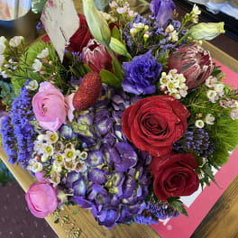 Mixed bouquet with red and pink roses, purple blooms, and green buds