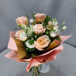Bouquet of peach and white roses wrapped in pink paper