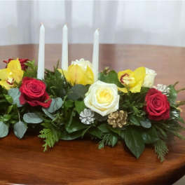 Low floral centerpiece with roses, orchids, and three white candles