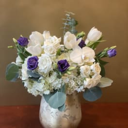 White and purple flowers arranged in a silver vase