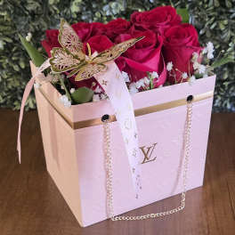 Pink roses in a decorative gift box with a ribbon and butterfly ornament
