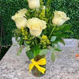 White roses in a glass vase with a yellow ribbon