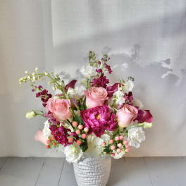 Pink and white floral arrangement in a textured white vase