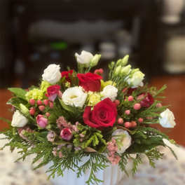 Red and white rose arrangement in a white vase