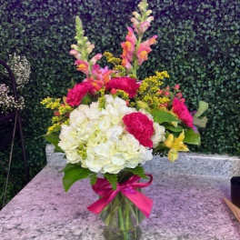 Bouquet of white and pink flowers in a glass vase with a pink ribbon