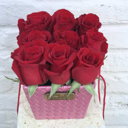Red roses arranged in a pink textured box