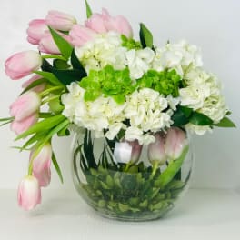 Pink tulips and white hydrangeas in a round glass vase