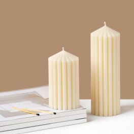 Two cream pillar candles on a white surface with matches nearby