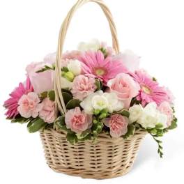 Pink and white flowers arranged in a wicker basket