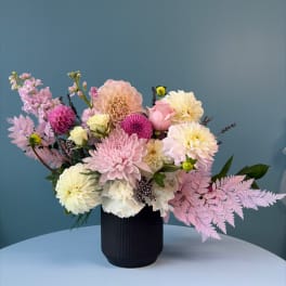 Pink and cream flower arrangement in a black vase