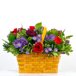 Mixed bouquet in a woven basket with red and purple flowers