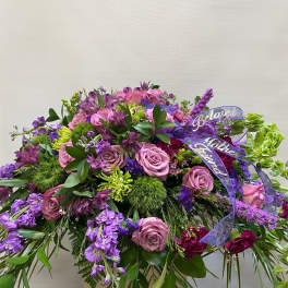 Large purple and pink floral spray with ribbon on a stand