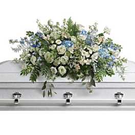 White and blue floral casket spray on a silver casket