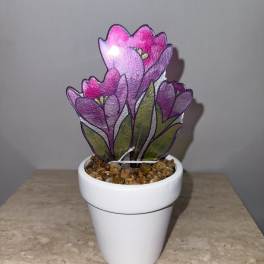 Purple flower-shaped decorative plant in a white pot with pebbles