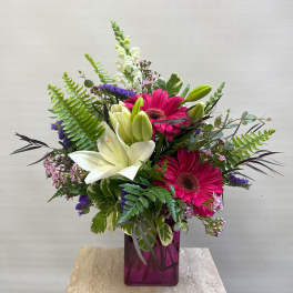 Bouquet of pink gerbera daisies and white lilies in a purple vase