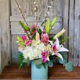 Pink lilies and roses in a blue vase with white hydrangeas