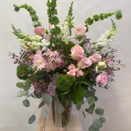 Tall bouquet of pink roses and white snapdragons in a glass vase