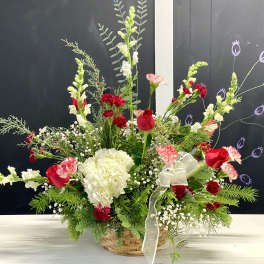 Basket arrangement with red and white flowers and a sheer ribbon