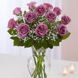 Lavender roses in a clear glass vase with baby's breath