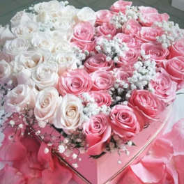 Pink and white roses arranged in a heart-shaped box