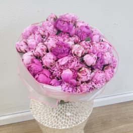 Large pink bouquet of peonies wrapped in translucent paper