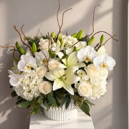 White lilies, orchids, roses, and hydrangeas in a white vase