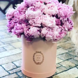 Pink peonies arranged in a blush round box
