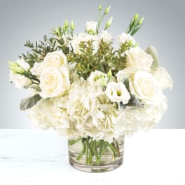 White roses and carnations arranged in a clear glass vase