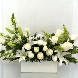 White roses and lilies arranged in a white rectangular box