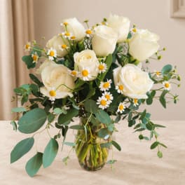 White roses and small daisies in a glass vase