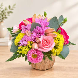 Pink and yellow mixed flower arrangement in a textured vase