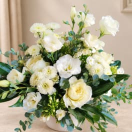 White floral arrangement in a low white vase with roses and mums