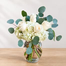 White roses and hydrangeas in a glass vase with eucalyptus