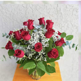 Bouquet of red roses with white baby's breath in a glass vase