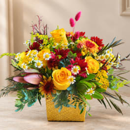 Bright mixed bouquet in a yellow textured vase with yellow roses and red flowers