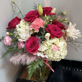 Bouquet of hot pink roses, white hydrangeas, and pink carnations in a glass vase