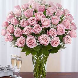 Pink roses arranged in a clear glass vase with baby’s breath